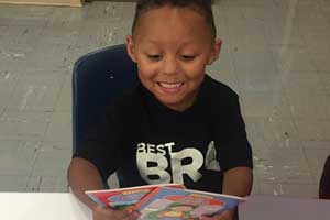 Pre-K student holding books received from Barb's Books Initiative