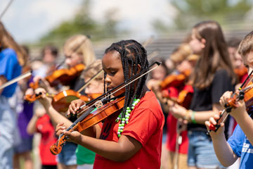 Girl playing violin outside during the 50th Annual Suzuki Festival