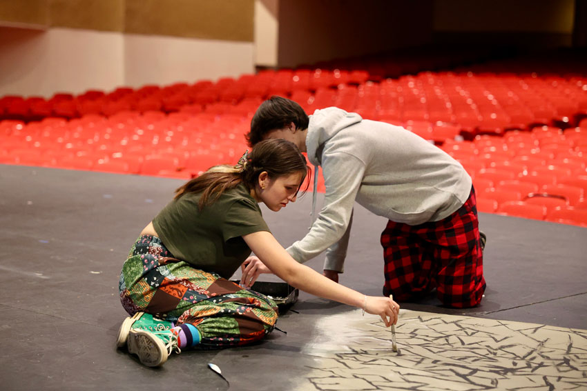 Two students painting set piece for play