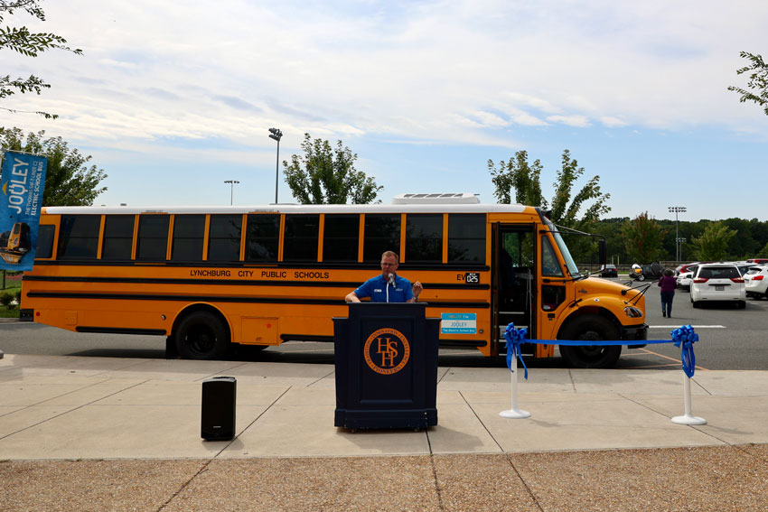 Man standing at podium in front of new EV bus