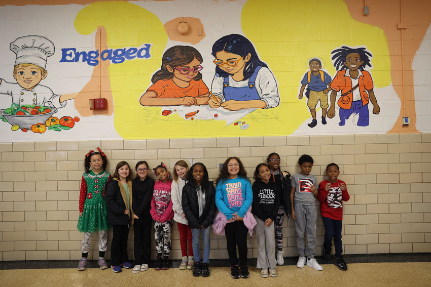 HEs students in front of school mural