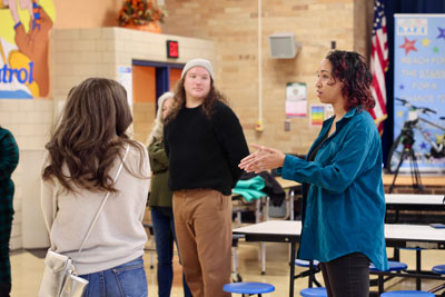 Artist speaking to group from J.Crew associates in cafeteria