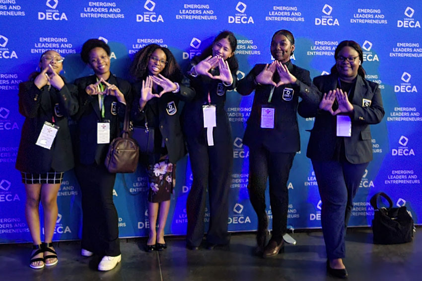 Six students standing in front of DECA backdrop