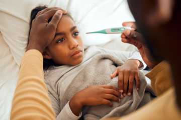 Sick girl with adult checking thermometer